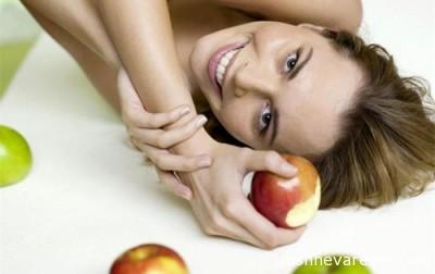 Woman lying on bed with apples, smiling